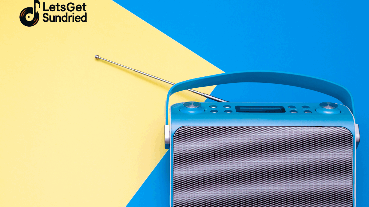 "Sebuah speaker bluetooth berwarna abu-abu dengan grill speaker di bagian depan, diletakkan di atas permukaan biru dan kuning yang kontras, menggambarkan elemen berita musik viral."