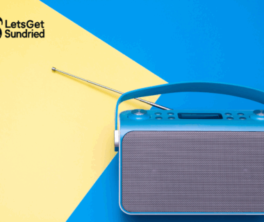 "Sebuah speaker bluetooth berwarna abu-abu dengan grill speaker di bagian depan, diletakkan di atas permukaan biru dan kuning yang kontras, menggambarkan elemen berita musik viral."