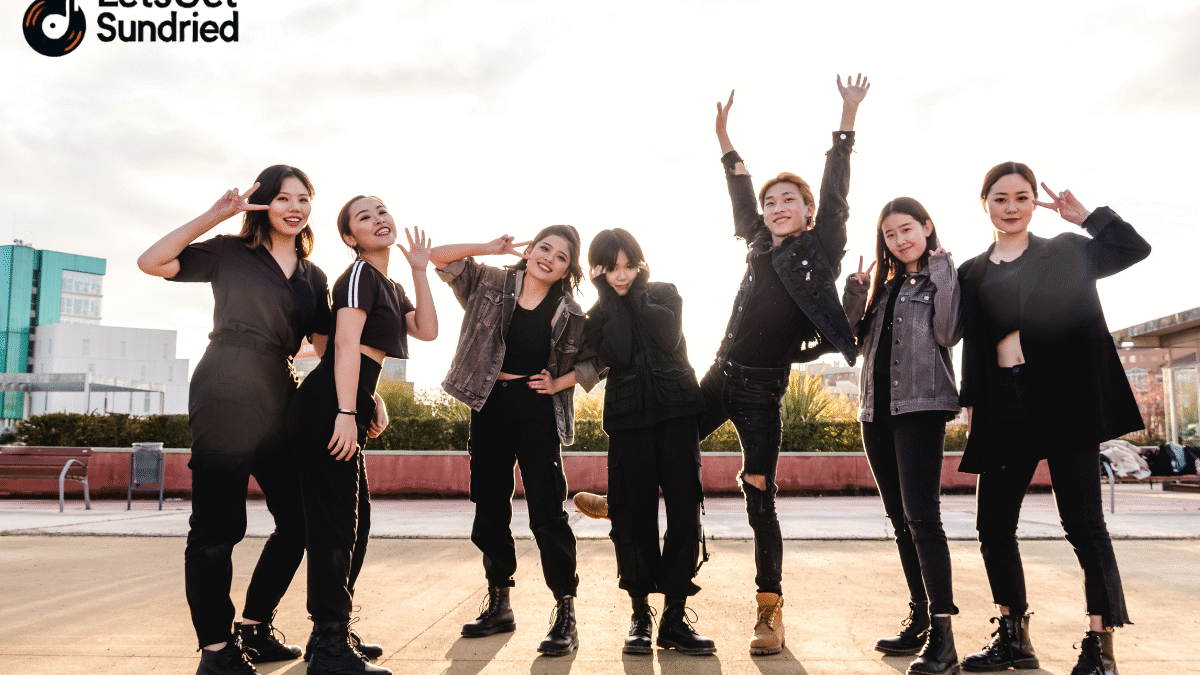 Sekelompok anggota grup genre musik K-Pop berpose ceria dengan latar belakang warna-warni.
