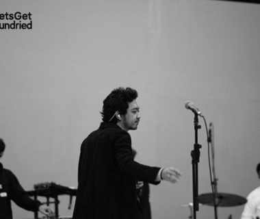 Foto hitam putih Pamungkas sedang menyanyikan lagu 'To The Bone' di atas panggung dengan pencahayaan dramatis, merepresentasikan inti dari kisah di balik MV.