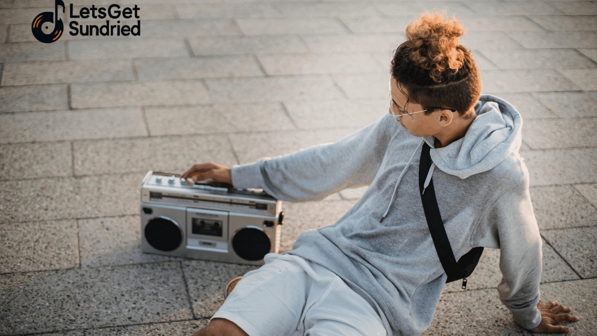 Orang duduk di tepi pantai dengan laptop dan headphone sambil memutar playlist santai