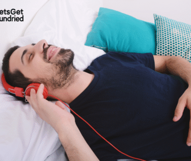 Pria sedang mendengarkan musik dengan earphone sambil tidur nyenyak, menunjukkan efek menenangkan dari playlist tidur nyenyak.