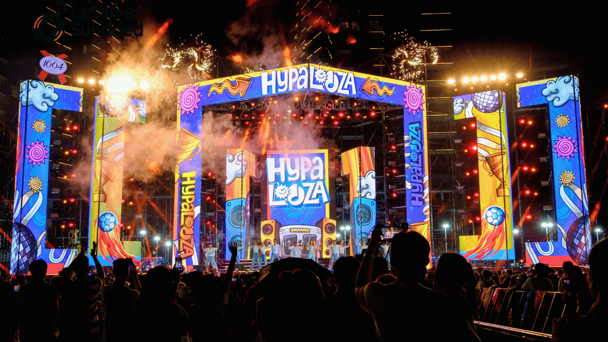 Panggung konser LED warna-warni menyala, penonton memadati area malam hari