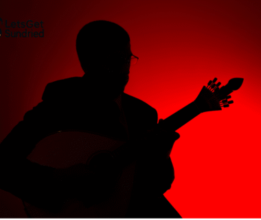 Siluet musisi baru Indonesia sedang memainkan gitar di atas panggung dengan latar merah.