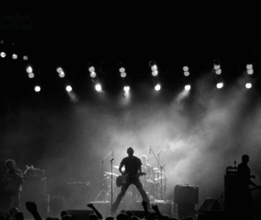 "Siluet band rock tampil di panggung dengan pencahayaan dramatis, menggambarkan sejarah musik rock dan energinya."