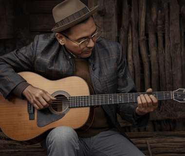 Musisi blues tua memainkan gitar resonator di teras kayu saat senja